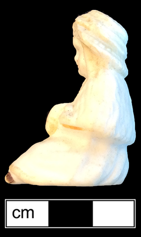 Small sitting doll, made of bisque porcelain, with the legs broken off. 4.75cm x 2.75cm x 3cm, from 18BC27.